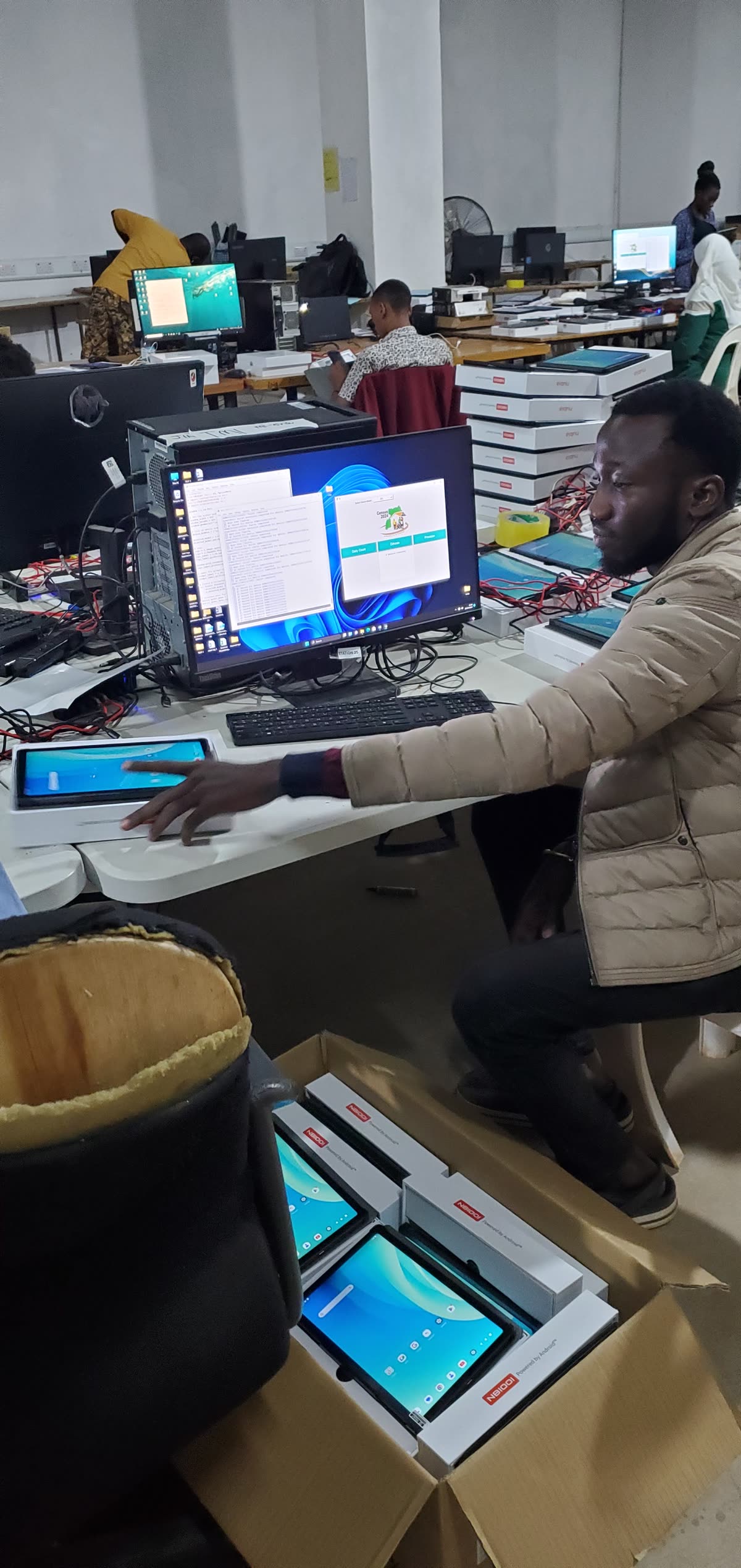 Charles Oriokot testing a tablet beside configured devices and workstations